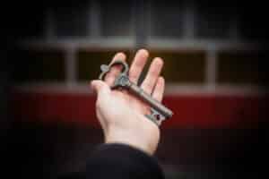 A hand holding an old key in front of a wooden door